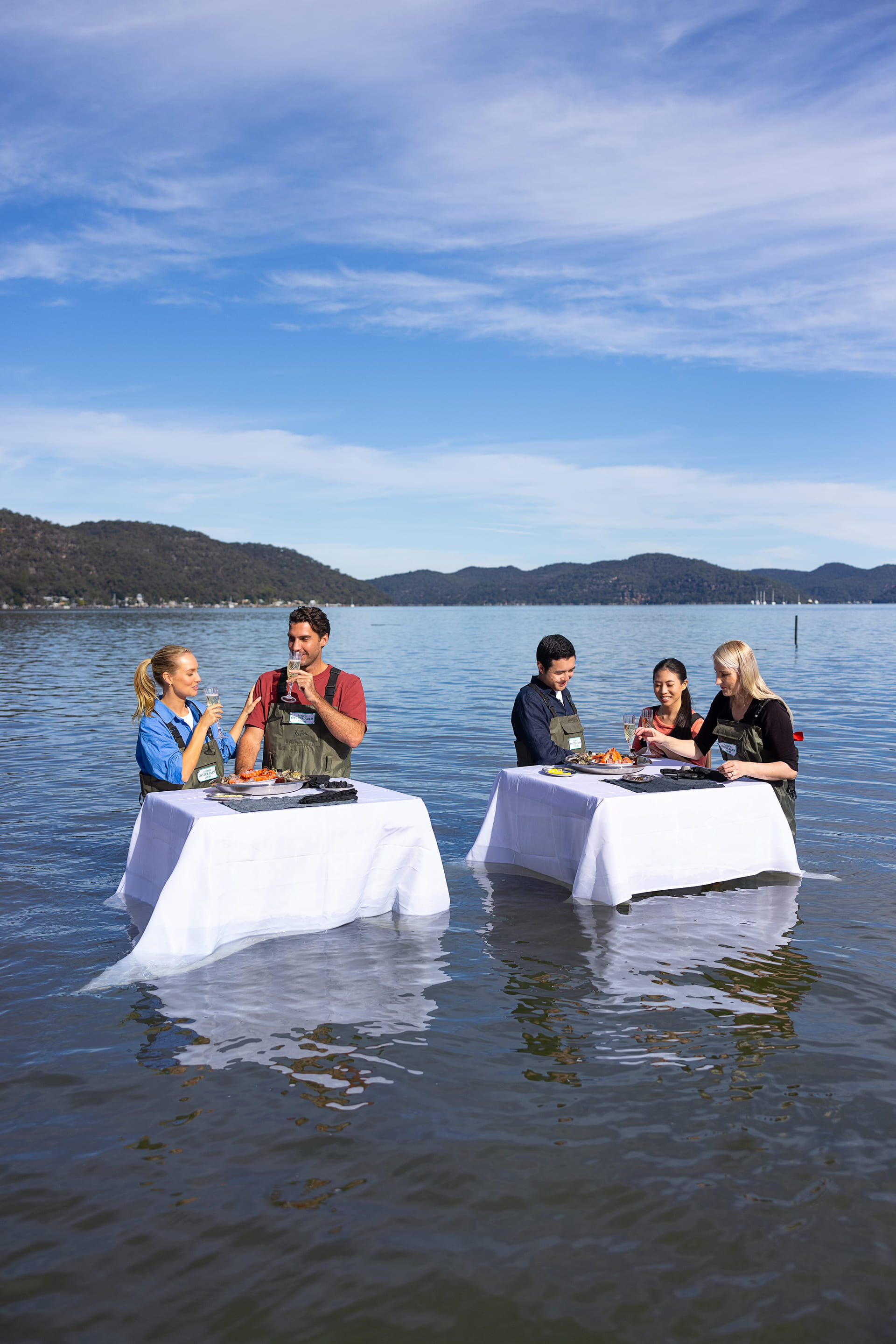 Two groups enjoying oysters and champagne at in water tables